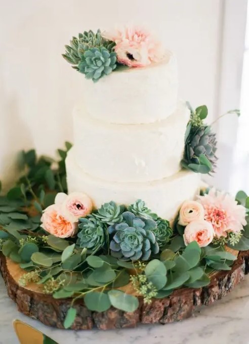 a white textural buttercream wedding cake with a greenery wreath, blush and light pink blooms and large succulents is a brilliant solution for a modern wedding with much greenery