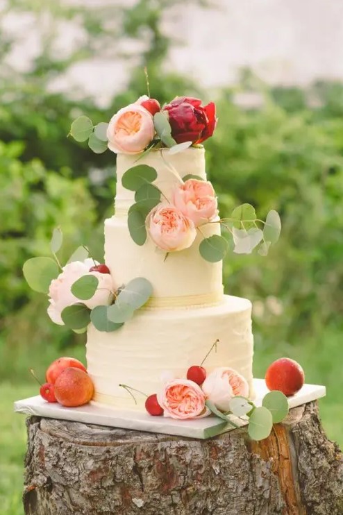 a white textural buttercream wedding cake with blush and burgundy peonies, greenery and some fresh fruit is a lovely idea for a summer wedding
