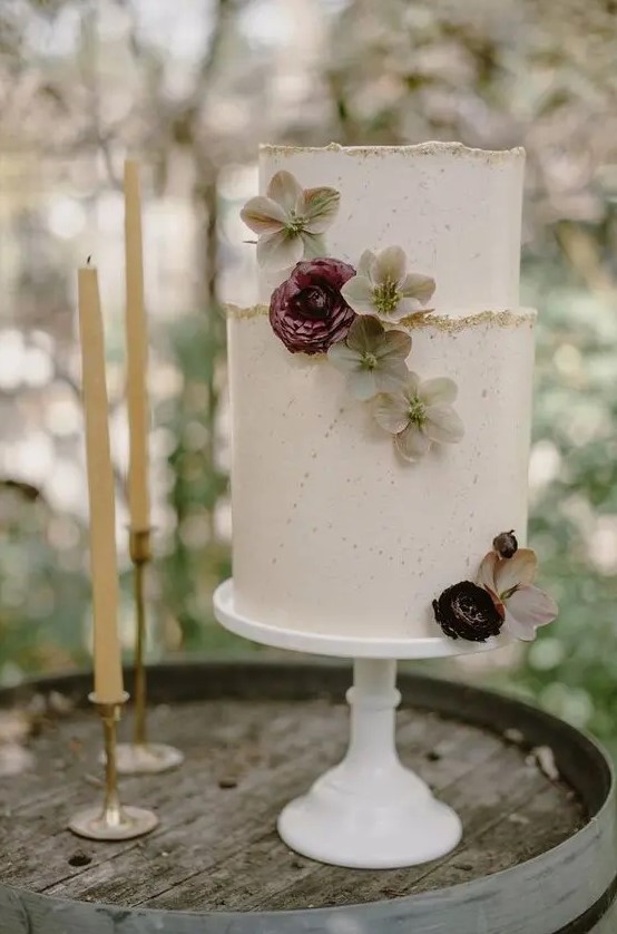 a white textural wedding cake with a gold glitter edge, fresh blooms is an elegant and romantic piece for a summer or fall wedding