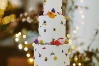 117 a white textural wedding cake with bright pressed blooms and pink macarons is a lovely idea for a spring or summer wedding