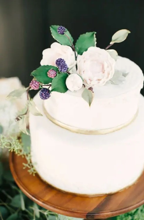 a white wedding cake with a gold ribbons, neutral blooms and sugar foliage plus berries on top for a summer wedding