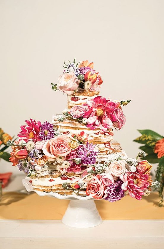 a beautiful waffle wedding cake with strawberries, pink and purple blooms and sugar powder is a lovely idea for a summer wedding