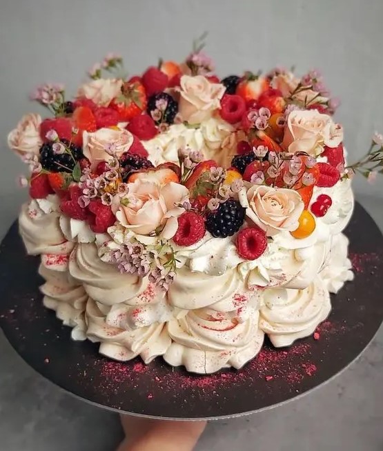 a gorgeous pavlova wedding cake topped with pink and blush blooms, with fresh berries and pink glitter is amazing for a summer wedding