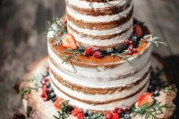 19 a naked wedding cake topped with sugared berries, greenery served on a wood slice for a rustic wedding
