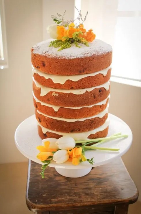 a naked wedding cake topped with greenery, lavender and white and yellow blooms is a beautiful idea for a spring or summer wedding