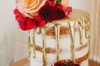 26 a small naked wedding cake with gold drip, pink, red and burgundy blooms, a gold calligraphy topper is utterly romantic