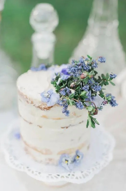 a spring or summer naked wedding cake topped with blue blooms is a cool idea for a pastel wedding
