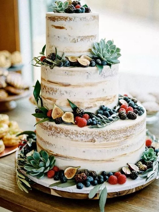 a yummy naked wedding cake topped with berries, greenery, fruits and succulents is a lovely idea for a spring or summer wedding