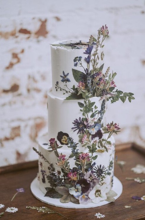 a boho summer three-tier wedding cake with dried blooms and leaves, pressed and dimensional, looks beautiful