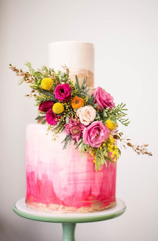 a bold pink watercolor wedding cake with brushstrokes, gold brushstrokes, bold pink, yellow and orange blooms and greenery
