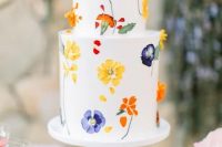 43 a bold white buttercream wedding cake with colorful pressed flowers and leaves is amazing for a spring or summer wedding