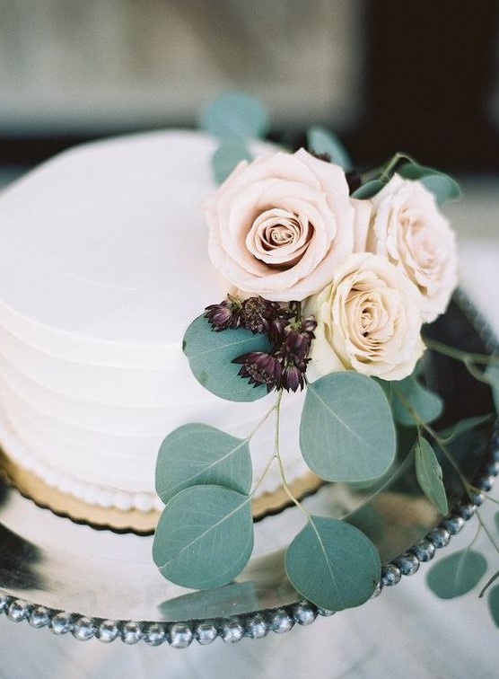 a buttercream-frosted wedding cake with roses and greenery is a very elegant and chic idea
