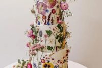 58 a fantastic wedding cake covered with white buttercream and with bright dried flowers and leaves pressed to it and attached for a voluminous look