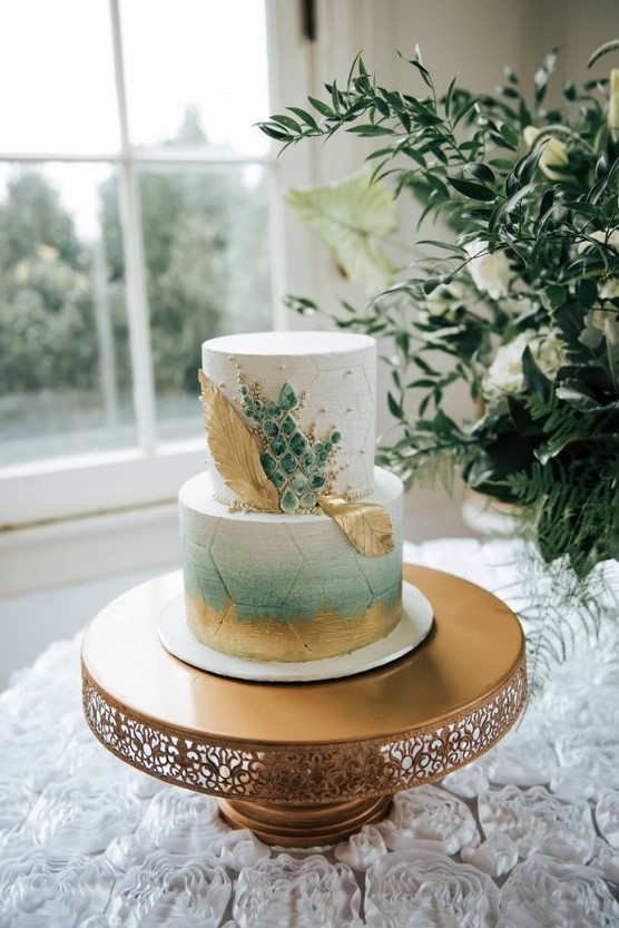 a fantastic wedding cake with a white and an ombre green tier, gold brushstrokes and leaves and green marble-like pieces