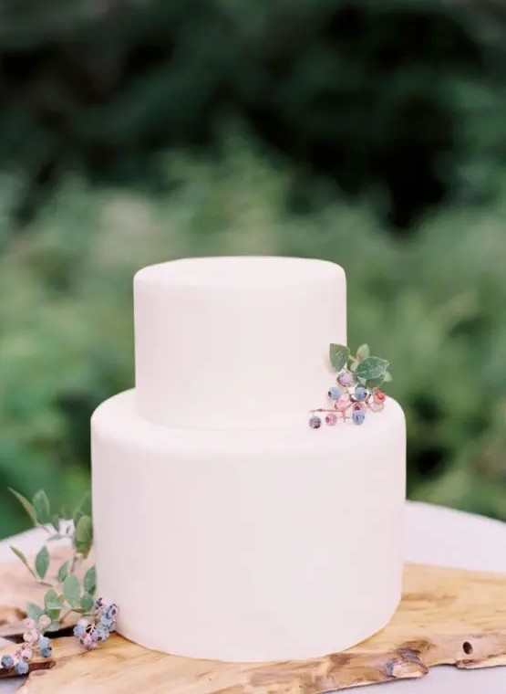 a minimalist plain white wedding cake topped with some berries for a modern natural or minimalist wedding