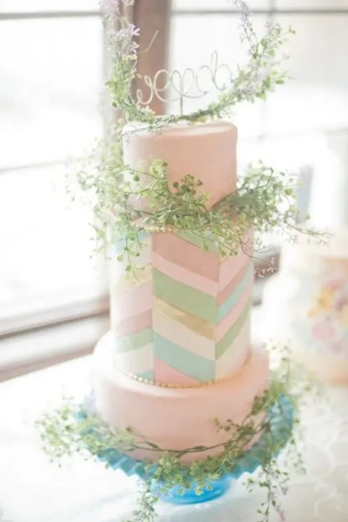a quirky wedding cake in blush with colorful chevron detailing and lots of greenery for a bright spring or summer wedding