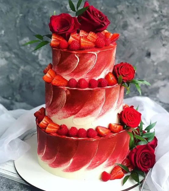 a red and white textural wedding cake topped with red roses and greenery and strawberries and rapsberries is a gorgeous idea for a modern wedding