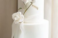 83 a refined and chic white wedding cake with a white rose branch with a gilded stem and a ribbon is gorgeous