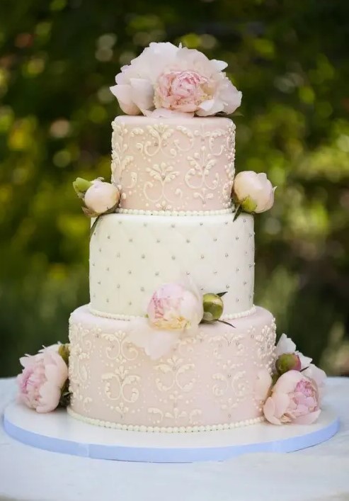 a refined white and blush wedding cake with gold detailing, blush roses and peonies is a fantastic and chic idea for a summer wedding