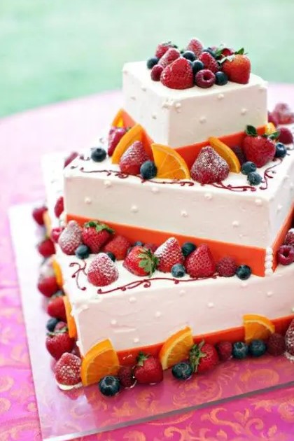 a square wedding cake with bold orange ribbons and bright berries and fruit is a gorgeous idea for a bold summer wedding
