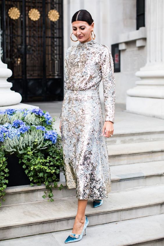 a NYE wedding guest outfit with a sequin A-line midi dress with a high neckline, blue velvet shoes and statement earrings