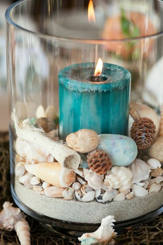 a beach wedding decoration of seashells, pinecones, driftwood, beach sand and a teal candle is bold and cool