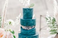 a bold blue beach wedding cake accented with crystals, leaves and dried herbs is lovely and bright