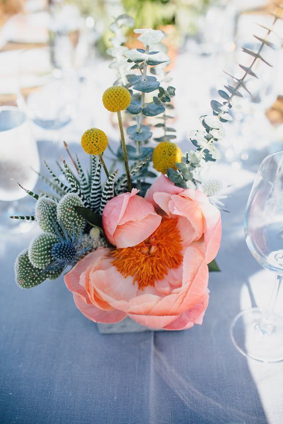 a bright summer wedding centerpiece of billy balls, a pink peonies, thistles, cacti and eucalyptus