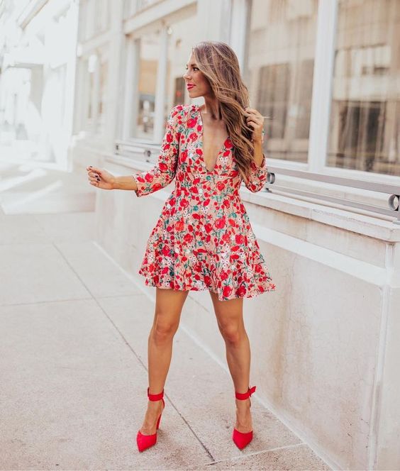 a colorful floral mini A-line dress with a plunging neckline, short sleeves and red shoes with ankle straps plus a red lipstick
