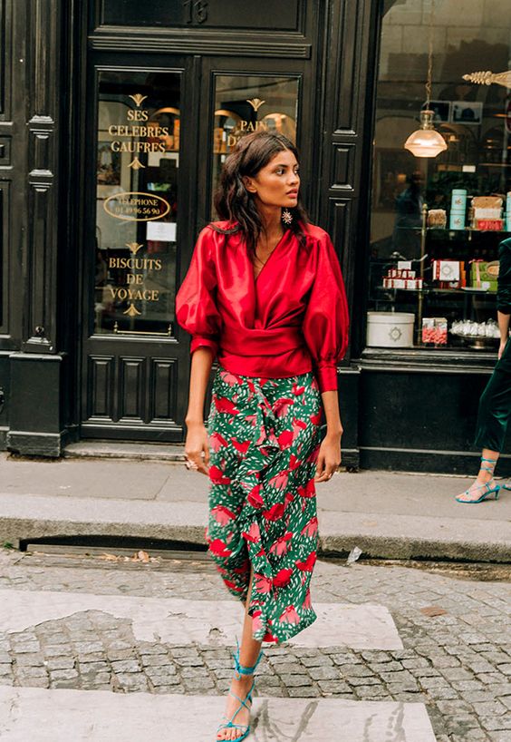 a deep red puff sleeve blouse, a green and red floral midi skirt, blue strappy heels for a fall wedding in bright shades