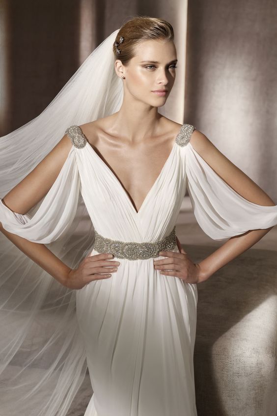 a draped wedding gown with cutout sleeves, embellished shoulders and a belt plus a deep neckline and a long veil