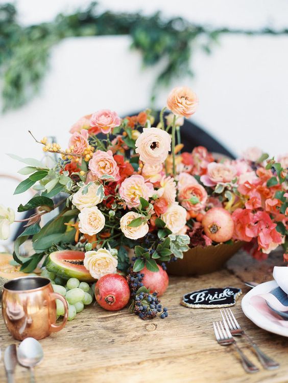 a gorgeous lush wedding centerpiece of peachy, blush and red  blooms, berries, pomegranates and grapes