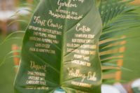 a large leaf with gold calligraphy is a creative and cool wedding menu for a tropical wedding