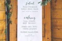 a long paper wedding menu with a greenery and neutral bbloom runner over it for a romantic wedding