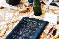 a menu printed on a dark napkin with gold letters is a qquirky and whimsy touch to the space