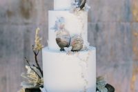 a refined beach wedding cake with pearls, seashells, blue flowers, corals is a gorgeous option for a modern beach wedding