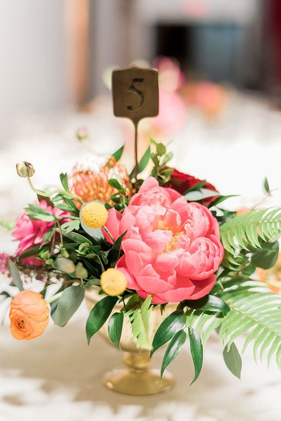 a romantic colorful summer wedding centerpiece with orange and coral pink blooms, billy balls and a table number