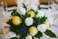 a simple and refreshing summer wedding centerpiece of white roses, lemons, privet berries and foliage is lovely