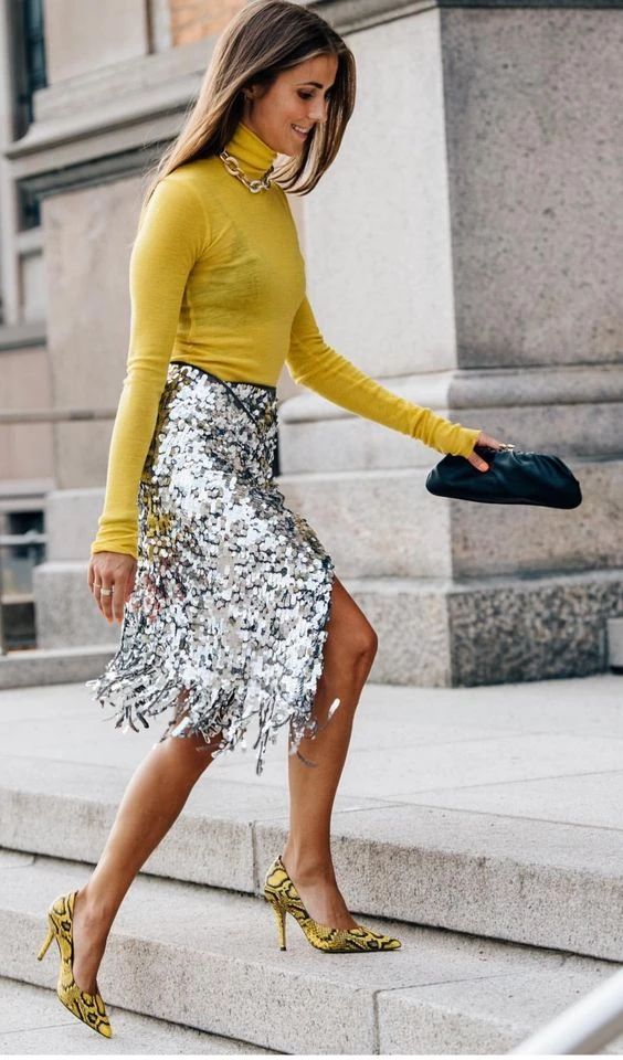 a sunny yellow turtleneck, a silver fringe skirt, a chain necklace, yellow snakeskin print shoes and a black clutch