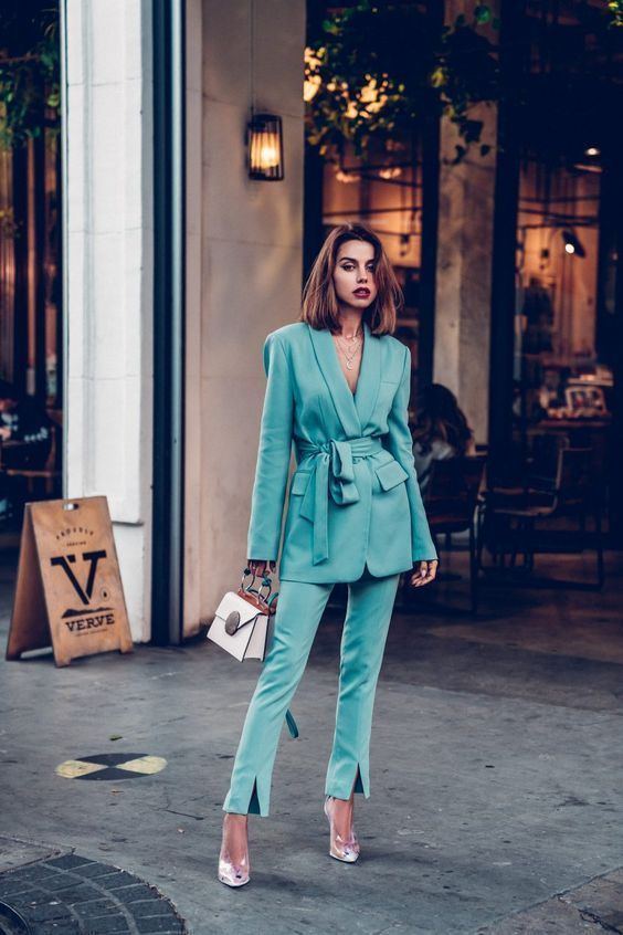 a turquoise pantsuit with an oversized blazer with a sash and pants with slits, sheer shoes and a white bag are lovely