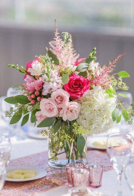 a vibrant wedding centerpiece of white, light and hot pink blooms, berries and foliage is lovely and chic