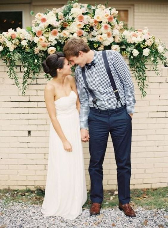 a vintage-inspired groom's look with navy pants, a plaid shirt, navy suspenders and a plaid bow tie plus brown shoes