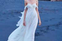 an off the shoulder flowy wedding dress with a draped embellished bodice and a flowy skirt