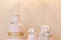 white wedding cake stands of various height, candles and blush and gold cakes with neutral sugar blooms
