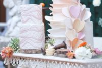 wood slices as cake stands for a whole arrangement of colorful wedding cakes with blooms and hearts will give a rustic feel to the sweet table