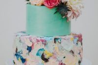 a beautiful colorful wedding cake with a mint green and bold textural brushstroke tier, bold blooms and thistles on top