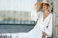 a beautiful destination bridal look with a flowy A-line wedding dress with a plunging neckline, statement earrings and a wide brim hat for a vacation feel