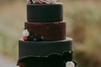 a black and burgundy wedding cake with berries and blush blooms for a modern and chic fall wedding with a touch of moody color