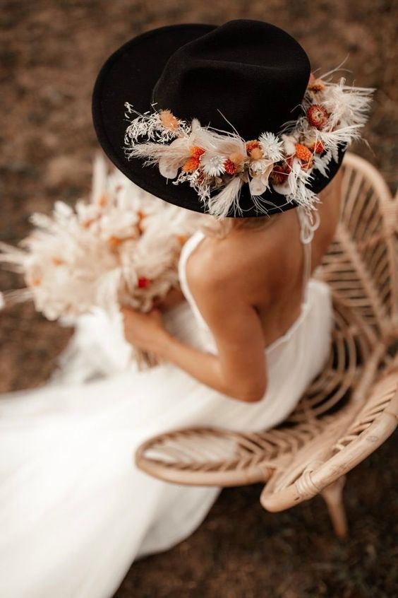 a black bridal hat decorated with bright dried blooms and grasses is a gorgeous idea for a boho no veil bride