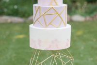 a blush and lilac wedding cake with gold geometric patterns, watercolors and gold 3D figures is a chic and bold idea